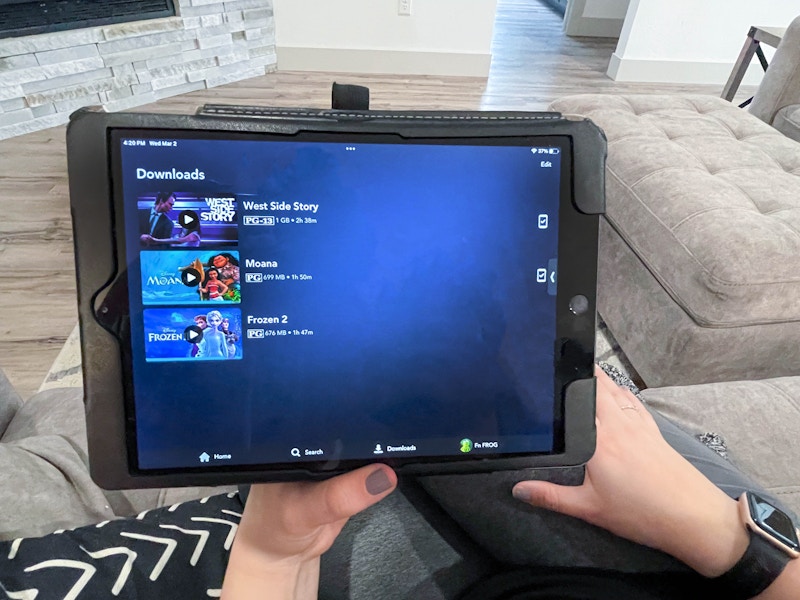 woman holding tablet with disney plus downloads on screen