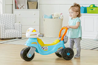 Lifestyle image of Vtech baby/toddler motorbike (toddler pushing the motorbike in home setting)