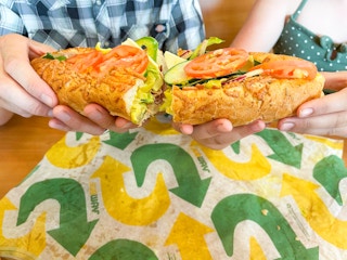 subway footlong with two people holding each half