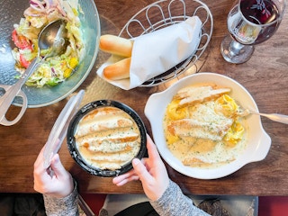 a table full of food with a person putting a lid on a to go container