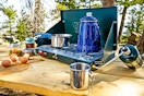 Lifestyle image of the Coleman 2-Burner Propane Stove being used outdoors to cook up a meal