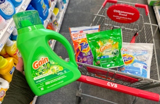 A hand holding a bottle of Gain detergent.