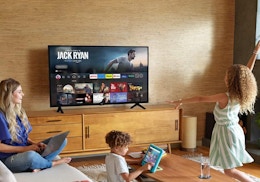 a woman and two kids in a room watching TV