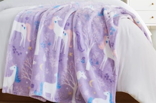 a unicorn throw blanket on a bed
