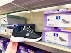 hand holding a skechers shoe in front of a target shelf