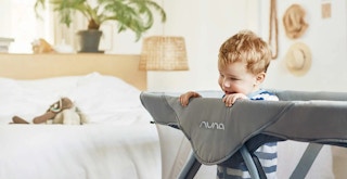 toddler standing in nuna aire playard and travel crib feature