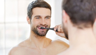 A man brushing his teeth with an electric toothbrush.