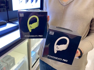 A woman holding two boxes of Powerbeats Pro headphones
