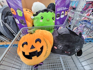 a pumpkin, bat, and frankenstein large squishy plushes in a cart at sam's club