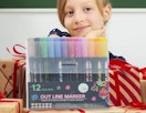 a pack of markers on top of presents in front of a little gril