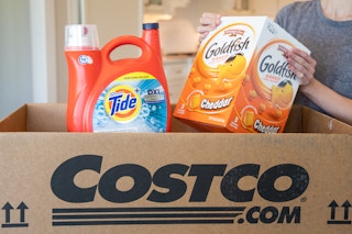 A person pulling gold fish crackers and tide from a Costco.com shipping box.