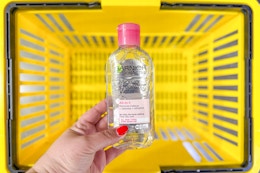 hand holding garnier micellar cleansing water above yellow basket