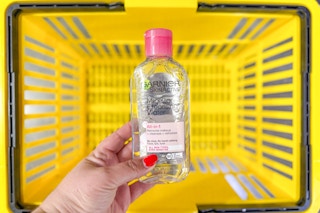 hand holding garnier micellar cleansing water above yellow basket