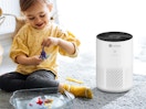 a little kid playing with toys next to an air purifier