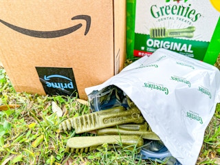 an Amazon box next to dog treats in grass outside