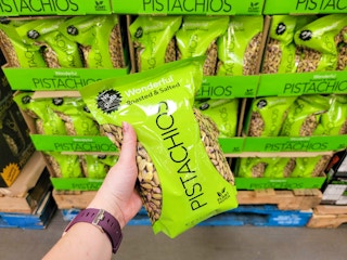 a person holding a bag of pistachios in store in front of display