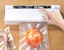 a person using a vacuum sealer on shrimp 