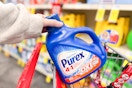 person placing a large bottle of purex detergent in a cart
