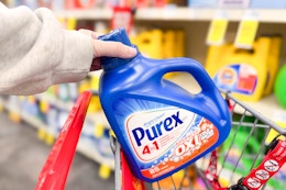 person placing a large bottle of purex detergent in a cart