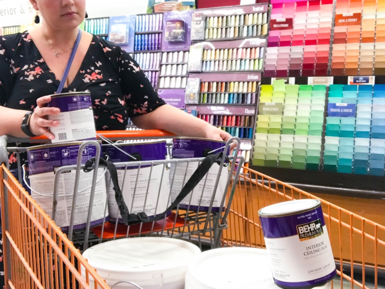 Person looking at paint cans next to paint color display