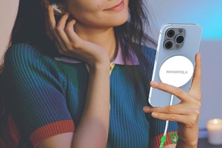 a woman holding a cell phone with a MagSafe charger