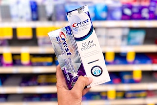 hand holding two crest premium toothpastes in a store aisle