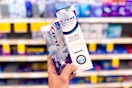 hand holding two crest premium toothpastes in a store aisle