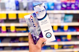 hand holding two crest premium toothpastes in a store aisle