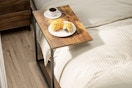 A c-shaped table is pushed close to a bed so the surface of the table is conveniently over the bed.