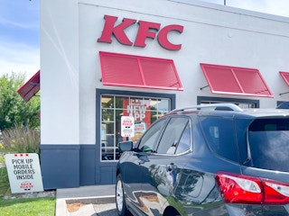 A KFC restaurant exterior with a car parked in front.