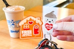 a hand holding a wendy's frosty key tag next to a frosty on a table