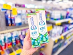 person holding 2 tubes of sensodyne kids toothpaste in an aisle
