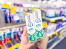 person holding 2 tubes of sensodyne kids toothpaste in an aisle