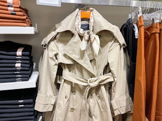 A jacket hanging from a store rack next to other pieces of clothing.