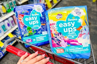 hand pushing cart with two packs of pampers easy ups