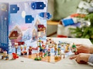 hands holding Christmas Lego figures on a table from an advent  calendar