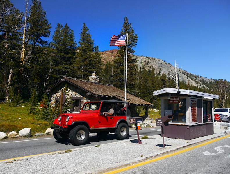 A jeep entering through a gate at the front of a national park.