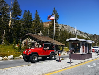 A jeep entering through a gate at the front of a national park.