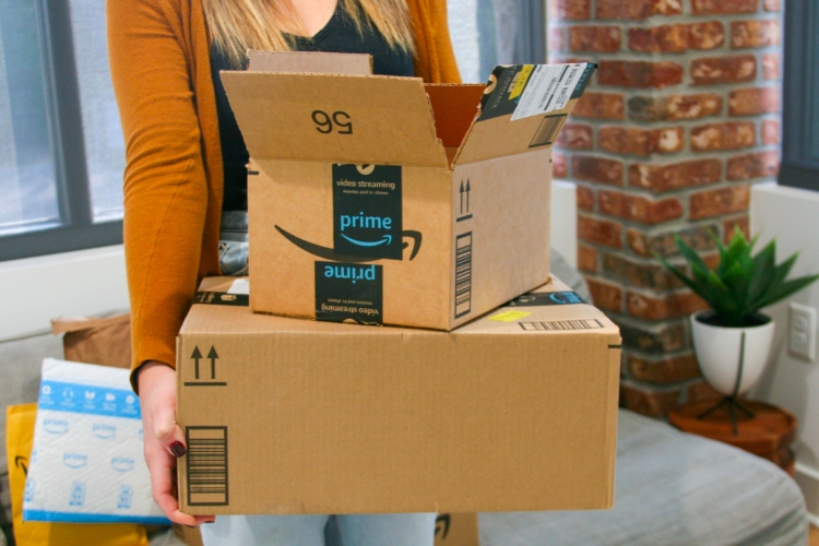 Close up of person holding open Amazon box stacked on larger Amazon box