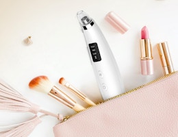 a blackhead vacuum in a pink pouch next to makeup brushes