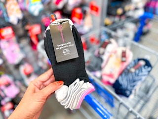 hand holding no boundaries 10 pack socks over walmart cart