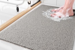 Lifestyle image of the Sixhome Non-Slip Shower Mat in the color gray (close up shot of someone standing on it with soap suds around feet)
