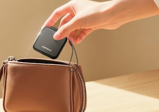 a hand putting a hand warmer in a purse