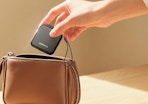 a hand putting a hand warmer in a purse