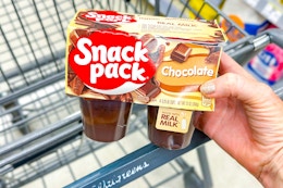 person holding a package of snack pack pudding over a cart
