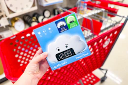 hand holding a kids' wake up light alarm clock in front a parked target cart