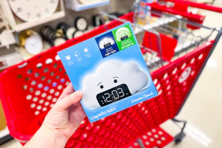 hand holding a kids' wake up light alarm clock in front a parked target cart