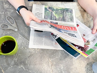 a person pulling coupon inset out of newspaper