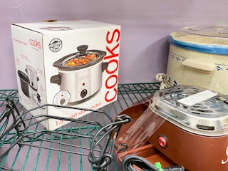 A Cooks slow cooker on a shelf in a thrift store.
