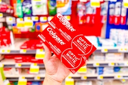 hand holding up two colgate toothpastes